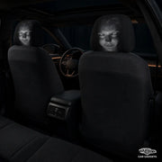Two horror-face Halloween headrest covers installed on the front seats of a dark car interior